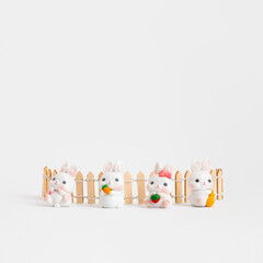 Obraz premium Little white rabbits on a white background. Creative greeting card design in a minimalist style. Chinese Lunar New Year composition for 2023. Year of the Rabbit.