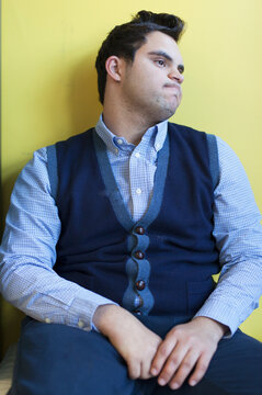 Middle Eastern man with Down Syndrome sitting against wall
