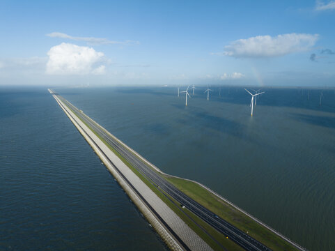 The Afsluitdijk flood defense system in the Netherlands between North Holland and Friesland closing the IJsselmeer off from the Wadden Sea. Dam and road infrastructure aerial drone view.