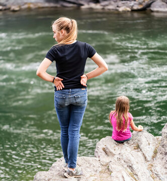 Two sisters spending time together at the edge of a river; British Columbia, Canada