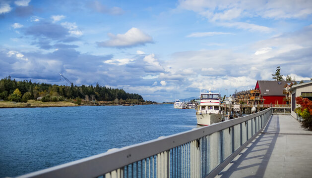 Boats in the harbour and walkway to colourful buildings on the waterfront of La Conner, a town on the coast of the Pacific Northwest; La Conner, Washington, United States of America