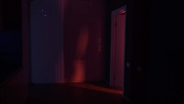 Man silhouette coming from the red light of opening door in dark room. mystery concept. Crime, evil and horror concept.