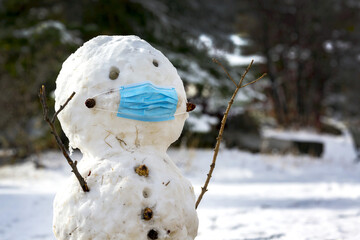 Snowman with medical face mask over nose and mouth; Calgary, Alberta, Canada