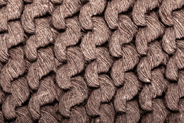 Detail of the handmade knitted pattern. Background and texture of knitted woolen or cotton fabric. Close-up. Brown color.
