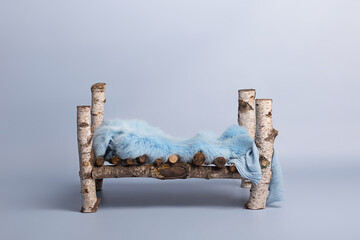vintage wooden bed on a blue background with a blue fur bedspread stands on a cloud. bed for newborns. background design for newborns