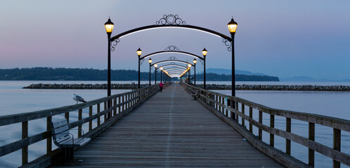 Lights illuminated along the White Rock pier at sunrise in BC, Canada; White Rock, British Columbia, Canada