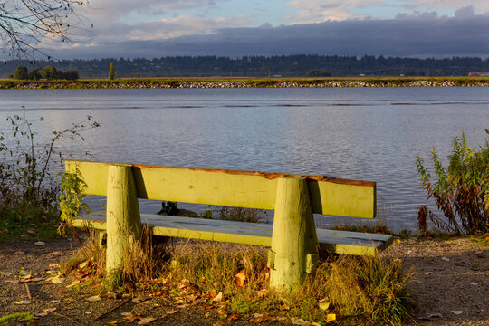 Bench along a path at the water's edge with a view of the Pacific Ocean water, off Marine Drive near Steward Historic Farmhouse in Surrey, BC, Canada; Surrey, British Columbia, Canada