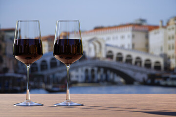 Two glass of red wine on Rialto bridge and Grand Canal background.