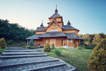 Ukraine. A wooden church in the middle of the park. A beautiful cobblestone road leads to it.