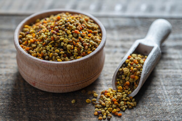 Raw organic bee pollen grains in scoop on wooden background, closeup