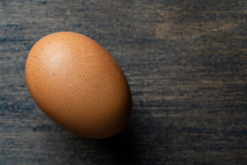 Fresh one brown egg in a wooden background from agriculture farm, closeup. Top view, copy space