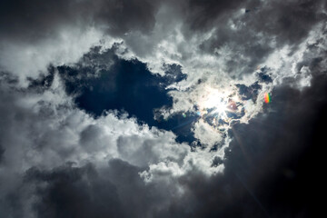 Dramatic storm clouds with blue sky opening and sunburst; Calgary, Alberta, Canada