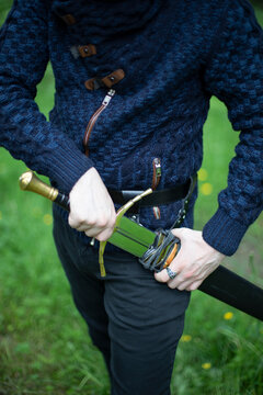 Young man holds a sword handle in the waist holster; Bothell, Washington, United States of America