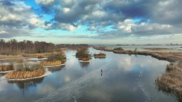 Ice skating on the Drontermeer lake in nature seen from above during a cold winter day in The Netherlands.