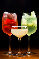 three cocktails in a dark bar