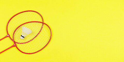 Two badminton rackets and badminton ball shuttlecock isolated on colored background for blog post header or announcement lay top view with copy space.