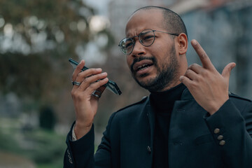 latin man talking on mobile phone with hands free or sending voice message