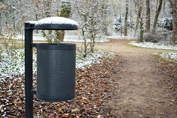 Bin in a public park on the street during winter covered snow.