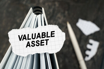 On the table is a notebook on which lies a piece of torn paper with the inscription - Valuable Asset