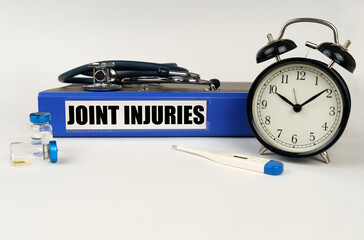 On a white surface, a thermometer, a stethoscope and a folder with the inscription - joint injuries
