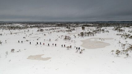  Aerial view on the rod of unidentified hikers walking with snowshoes the snowy bog landscape