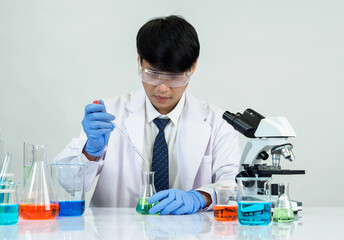 Asian male student scientist in reagent mixing laboratory In a science research laboratory with...