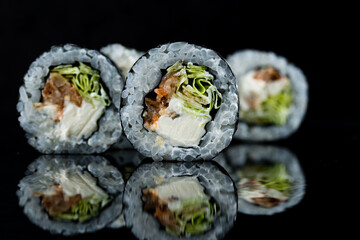 Set of sushi rolls with perch fish, cream cheese and iceberg lettuce on black.