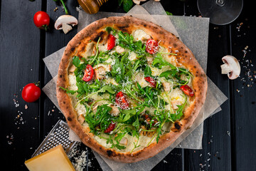Pizza with cheese parmesan, chicken, arugula, cherry tomatoes and spices.
