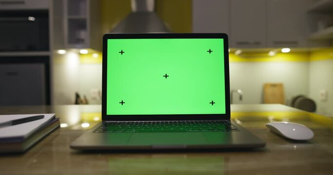 Modern laptop with blank green screen. dolly footage . Home interior modern kitchen background.Perfect to put your own image or video. Track points with perspective corner pin