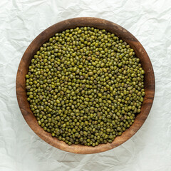 Green raw mung beans in a wooden bowl. Top view.