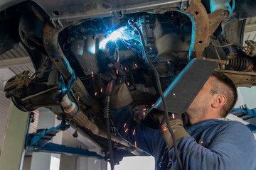 Skilled welder with mask doing the welding in a workshop.During the welding, there were a lot of...