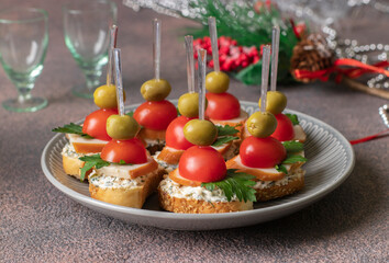Festive canapes with croutons, smoked chicken, olives and cherry tomatoes on brown background