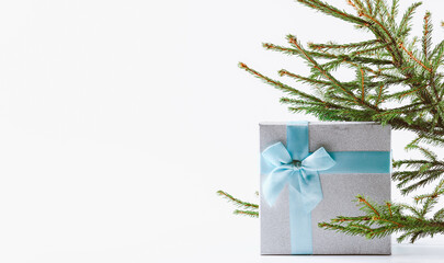 Christmas background. A box with a gift tied with a ribbon and a spruce branch.