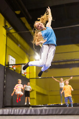 Naklejka na ściany i meble Happy emotional teenage girl having fun in indoor amusement park, bouncing on trampoline..