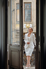 Fototapeta na wymiar a beautiful, confident woman in a white suit on the balcony of the old building.
