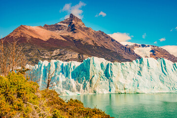 View over big Perito Moreno glacier in Patagonia with blue sky and turquoise water glacial lagoon, South America, Argentina, in Autumn colors