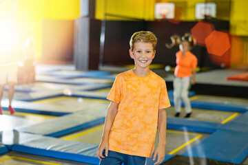 Portrait of smiling preteen boy spending time in modern inflatable amusement park, posing in trampoline arena.. - obrazy, fototapety, plakaty