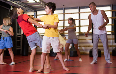 Girls and boys performing self-defence moves in gym during their group training.
