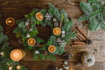 Christmas wreath made of natural branches, orange slices and New Year's decor on a wooden...