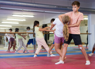 Obraz premium Preteen children working in pair mastering new self-defense moves at gym