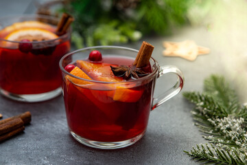 Two cups of christmas mulled wine or gluhwein with spices and orange slices on rustic table top view.