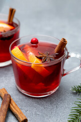 Two cups of christmas mulled wine or gluhwein with spices and orange slices on rustic table top view.