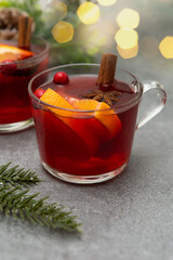 Two cups of christmas mulled wine or gluhwein with spices and orange slices on rustic table top...