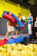 Fototapeta na wymiar Smiling children having funny wrestling by inflatable logs in indoor amusement park