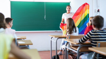 Positive female teacher explaining lgbt theme to children during lesson in class in secondary school