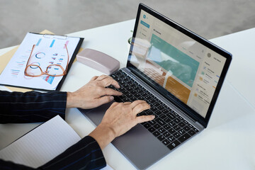 Close up of unrecognizable senior woman typing at laptop keyboard while working in office, copy space