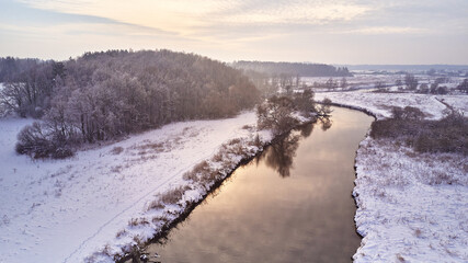 Winter river landscape, snow covered fields. Hoarfrost on trees, plants. Frosty morning. Sunny cloudy Misty weather. Cold season. Calm nature scene
