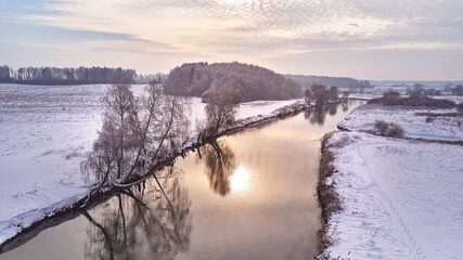 Winter river landscape, snow covered fields. Hoarfrost on trees, plants. Frosty morning. Sunny cloudy Misty weather. Cold season. Calm nature scene. - 555258870