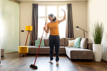 Cheerful Young Arab Woman In Headphones Having Fun While Cleaning At Home