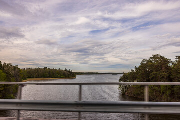 Beautiful blurred view of lake merging with blue sky on horizon during car driving over bridge. Sweden. Europe. 